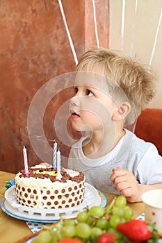 Little boy and birthday cake with blow out the