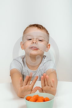 Little boy biting the carrot, isolated on white