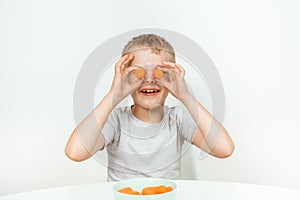 Little boy biting the carrot, isolated on white