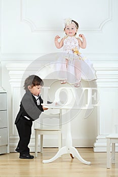 Little boy in black suit moving round table with