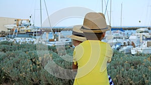 Little boy and blond girl in hats are playing catch-up on the yacht port