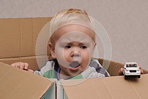 Little boy with blond hair sitting in a box