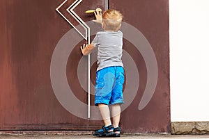 Caucasian baby boy tries to open the big door.