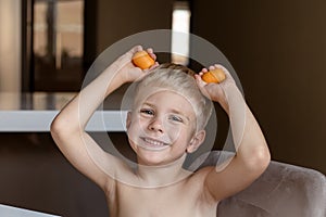 A little boy blonde plays with yellow capsules from kinder surprise, smiles, he is happy photo