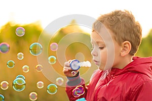 Little boy blowing soap bubbles outdoors