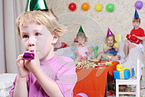 Little boy blows in party blowers at birthday