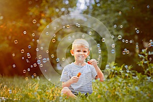 A little boy blows soap bubbles