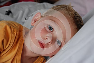 Little boy with blue eyes in bed