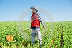Little boy with a butterfly net in hand runs across the green field. photo