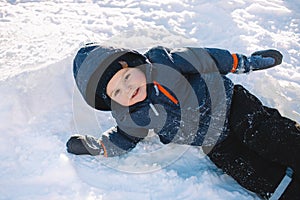 Little boy in blue jacket play with snow, winter holidays