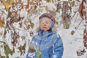 Little boy in a blue outwear having fun in the forest