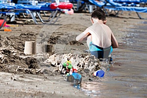 Little boy in blue sea and sand play