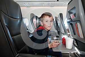 A little boy on board the plane eats chocolate candies while drinking water