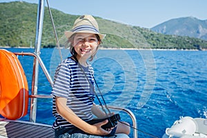 Little boy on board of sailing yacht on summer cruise. Travel adventure, yachting with child on family vacation.