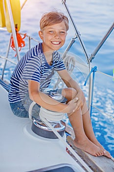 Little boy on board of sailing yacht on summer cruise. Travel adventure, yachting with child on family vacation.