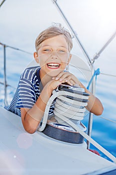 Little boy on board of sailing yacht on summer cruise. Travel adventure, yachting with child on family vacation.