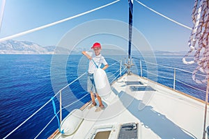 Little boy on board of sailing yacht on summer cruise. Travel adventure, yachting with child on family vacation.