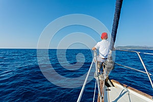 Little boy on board of sailing yacht on summer cruise. Travel adventure, yachting with child on family vacation.