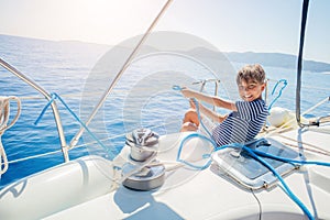 Little boy on board of sailing yacht on summer cruise. Travel adventure, yachting with child on family vacation.