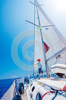 Little boy on board of sailing yacht on summer cruise. Travel adventure, yachting with child on family vacation.