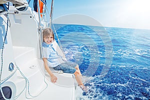 Little boy on board of sailing yacht on summer cruise. Travel adventure, yachting with child on family vacation.