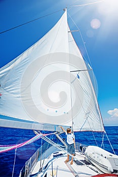 Little boy on board of sailing yacht on summer cruise. Travel adventure, yachting with child on family vacation.