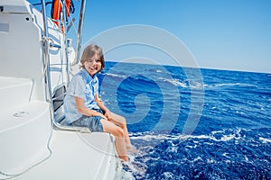 Little boy on board of sailing yacht on summer cruise. Travel adventure, yachting with child on family vacation.