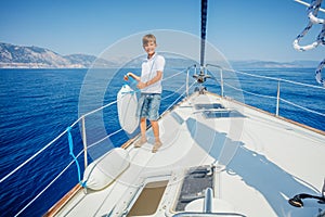 Little boy on board of sailing yacht on summer cruise. Travel adventure, yachting with child on family vacation.