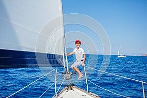 Little boy on board of sailing yacht on summer cruise. Travel adventure, yachting with child on family vacation.