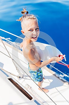 Little boy on board of sailing yacht on summer cruise. Travel adventure, yachting with child on family vacation.