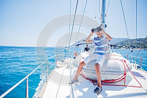 Little boy on board of sailing yacht on summer cruise. Travel adventure, yachting with child on family vacation.