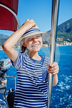 Little boy on board of sailing yacht on summer cruise. Travel adventure, yachting with child on family vacation.