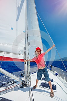 Little boy on board of sailing yacht on summer cruise. Travel adventure, yachting with child on family vacation.