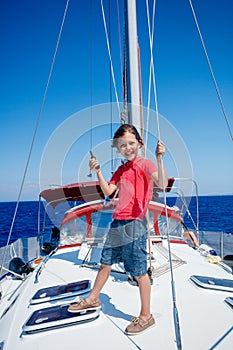 Little boy on board of sailing yacht on summer cruise. Travel adventure, yachting with child on family vacation.