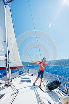 Little boy on board of sailing yacht on summer cruise. Travel adventure, yachting with child on family vacation.