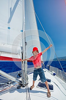 Little boy on board of sailing yacht on summer cruise. Travel adventure, yachting with child on family vacation.