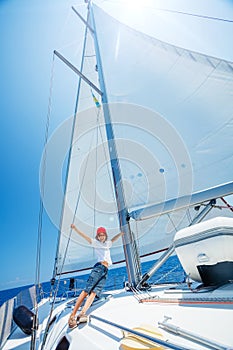 Little boy on board of sailing yacht on summer cruise. Travel adventure, yachting with child on family vacation.