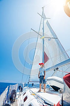 Little boy on board of sailing yacht on summer cruise. Travel adventure, yachting with child on family vacation.