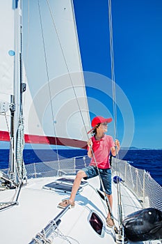 Little boy on board of sailing yacht on summer cruise. Travel adventure, yachting with child on family vacation.