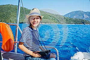 Little boy on board of sailing yacht on summer cruise. Travel adventure, yachting with child on family vacation.