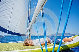 Little boy on board of sailing yacht on summer cruise. Travel adventure, yachting with child on family vacation. photo