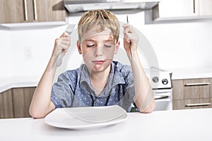 Little boy with bored grumpy expression sitting at a table