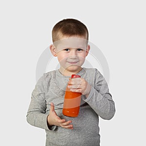 Little boy with bottle of orange carrot juice in hand