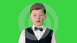 Little boy in a bow tie and waistcoat talking to the camera on a Green Screen, Chroma Key.