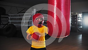 Little boy boxer kicking the punching bag with his legs from the turn