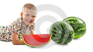 Little boy in a bright shirt lies near large whole watermelons a