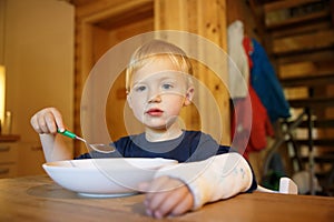 Little boy with a broken wrist eating at the table. Boy with a plaster on his arm