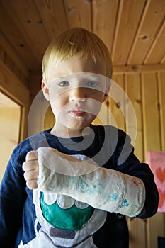 Little boy with a broken wrist at home. Boy with a plaster on his hand