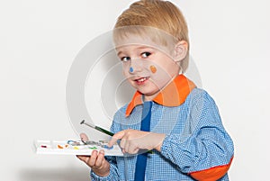 Little boy with brush covered in paint making funny face