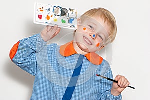 Little boy with brush covered in paint making funny face